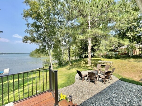 A deck with outdoor furniture overlooking a lake, surrounded by trees. - Relax and recharge! Cabin on a tranquil bay on Deer Lake is a perfect get away! (Deer River)