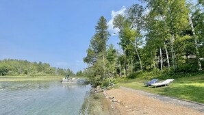 Vista al lago con aguas cristalinas, una playa de arena y sillas de descanso.