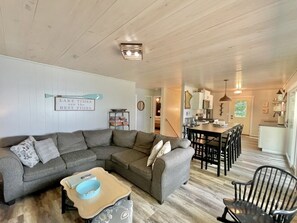 A cozy living room with a sectional sofa, a dining area with a wooden table and chairs, and a kitchen in the background. - Relax and recharge! Cabin on a tranquil bay on Deer Lake is a perfect get away! (Deer River)