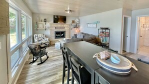 Amplia sala de estar con chimenea, comedor con una mesa larga y zona de estar acogedora con sofá y sillones.