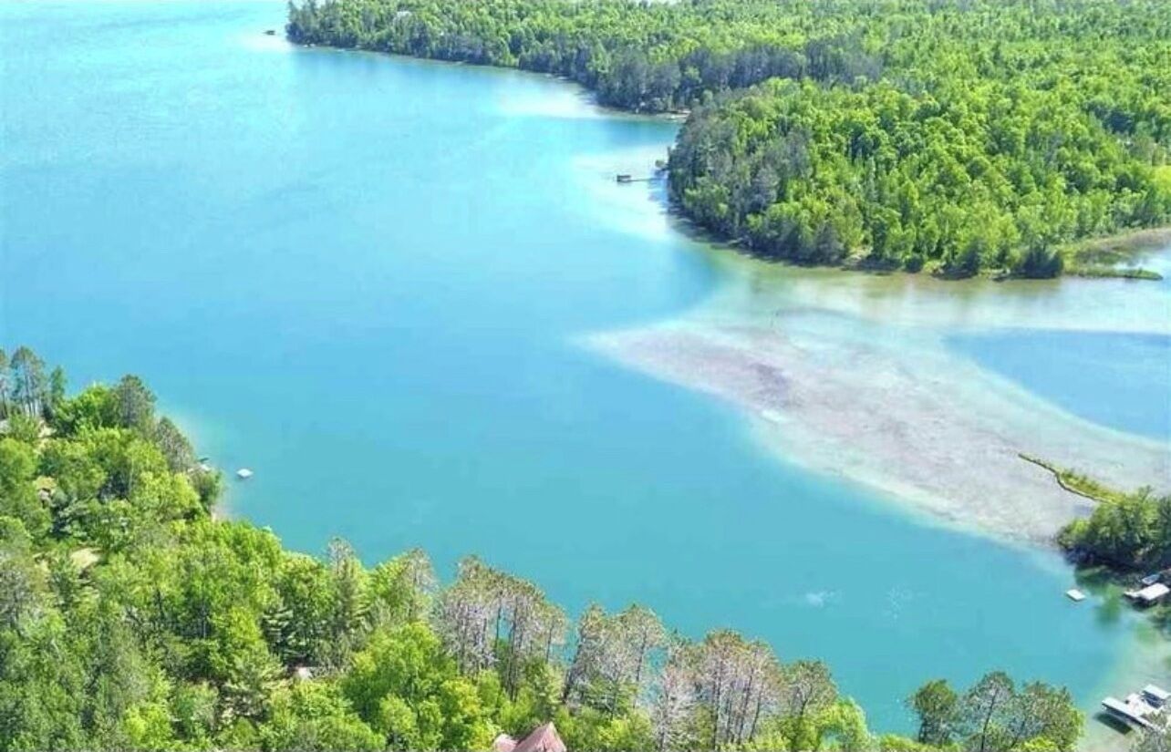 Paisaje costero con vista despejada al agua, una pequeña isla y abundante vegetación.
