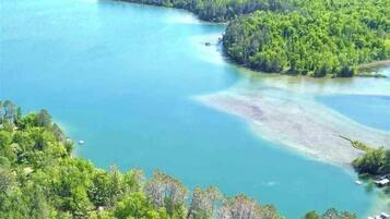 Paisaje costero con vista despejada al agua, una pequeña isla y abundante vegetación.
