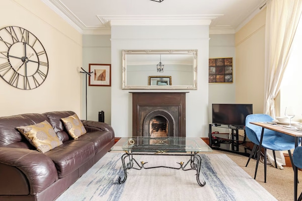 Our stylish living room with two leather sofas, a mechanical clock, a sleek coffee table, and modern amenities like a heater, air purifier, and wall mirror. Your cozy retreat awaits!