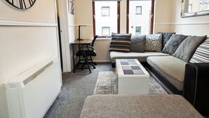 A cozy living room with a sofa, a small table, and a radiator. - 2 Bed Flat - Sleeps 4 - Parking - Wifi (Aberdeen)