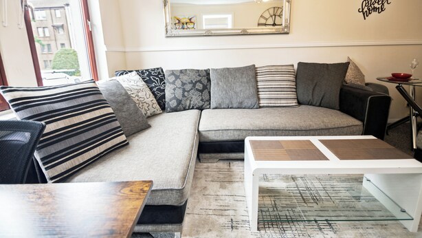 A modern living room with a sectional sofa, a coffee table, and a mirror on the wall. - 2 Bed Flat - Sleeps 4 - Parking - Wifi (Aberdeen)