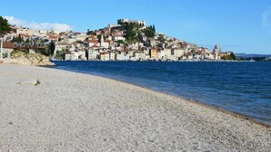A coastal town with a historic hilltop castle, a pebble beach, and a clear blue sky. - Vacation home Nina by Interhome (Šibenik/Dubrava)