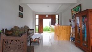 A spacious room with a wooden bench, a small table, and a cabinet with glass doors. - OYO 3906 Dalem Putu Sanjaya Syariah (Sleman)