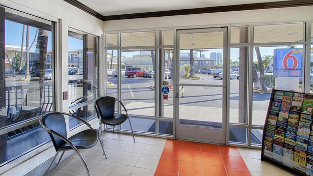 A hotel lobby with large glass doors, a seating area with chairs, and a display of local attractions.