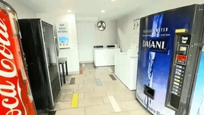 A hotel lobby with a Coca-Cola refrigerator, a Dasani water dispenser, and a clock on the wall.