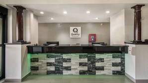 A hotel reception desk with a marble-like design, a sign reading 'Quality by Choice Hotels,' and a red emergency phone. - Quality Inn & Suites Fort Worth - Fossil Creek (Fort Worth)