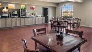 A spacious dining area with a wooden table and chairs, a kitchen area with appliances and a refrigerator, and a large window offering a view. - Quality Inn & Suites Fort Worth - Fossil Creek (Fort Worth)