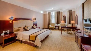 A hotel room with a large bed, a desk with a chair, a television, and a mirror. - Uchoice Hotel (Ganzhou)