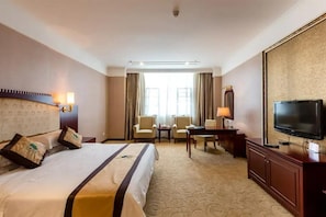 A hotel room with a large bed, two armchairs, a desk, a television, and a large window with curtains. - Uchoice Hotel (Ganzhou)