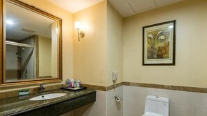A bathroom with a sink, mirror, toilet, and a framed painting on the wall. - Uchoice Hotel (Ganzhou)
