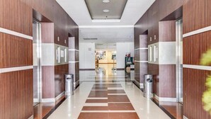 Un moderno vestíbulo de hotel con un pasillo central, paneles de madera y suelo de baldosas.