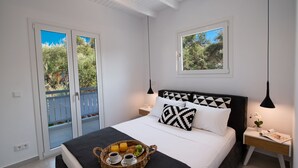 A bedroom with a bed, a bedside table with a lamp, a window, and a balcony with a view of trees. - High-end Luxury Apartment & Convenient Location (Tsoukalades)