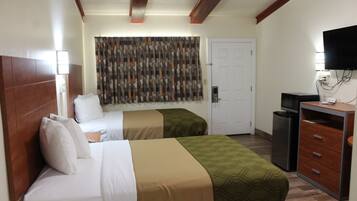Habitación de hotel con dos camas, televisión, escritorio y puerta.