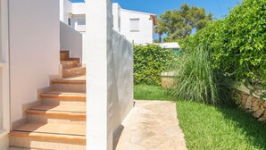 A staircase leading to a white building with a stone pathway and lush greenery.