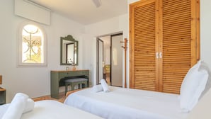 A hotel room with two beds, a desk, a mirror, and a large wooden wardrobe.