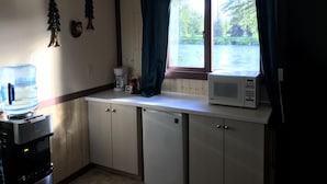 A kitchen with a water dispenser, coffee maker, microwave, and cabinets.