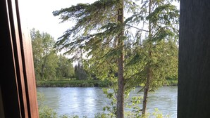 A wooden picnic table by a lake with trees in the background.