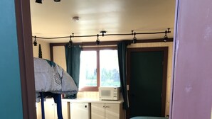 A compact room with a bunk bed, a small kitchenette, and a dining table.