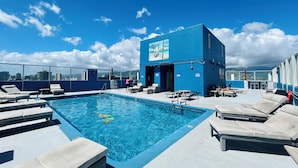 A rooftop pool area with lounge chairs and a building with a mural.