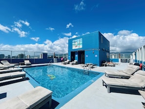 A rooftop pool area with lounge chairs and a building with a mural. - "STEPS AWAY FROM THE WAIKIKI BEACH STUDIO WITH OCEAN VIEW" (Honolulu)