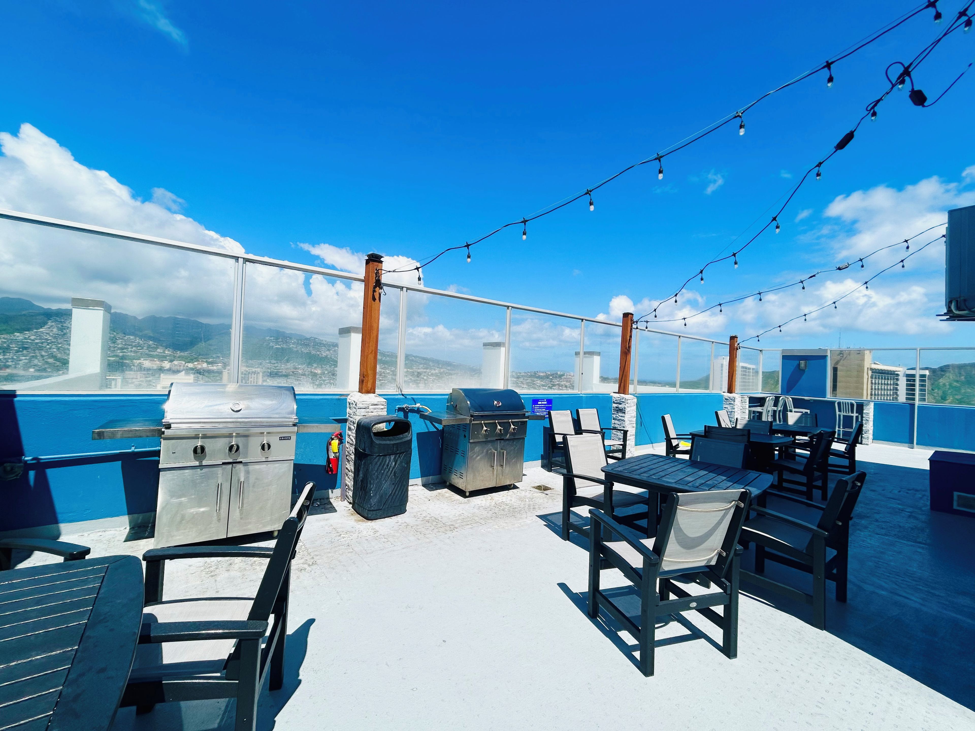 An outdoor deck with a barbecue area, seating, and a view of the city.
