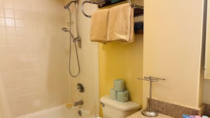 A bathroom with a bathtub, toilet, and a sink area with toiletries. - "STEPS AWAY FROM THE WAIKIKI BEACH STUDIO WITH OCEAN VIEW" (Honolulu)