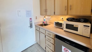 A compact kitchen with wooden cabinets, a microwave, a toaster, and a dishwasher. - "STEPS AWAY FROM THE WAIKIKI BEACH STUDIO WITH OCEAN VIEW" (Honolulu)