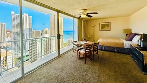 A hotel room with a balcony, a bed, a desk, and a chair.