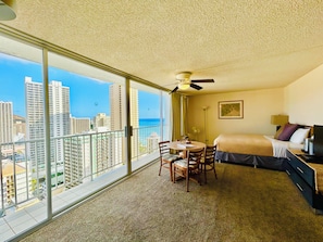 A hotel room with a balcony, a bed, a desk, and a chair. - "STEPS AWAY FROM THE WAIKIKI BEACH STUDIO WITH OCEAN VIEW" (Honolulu)