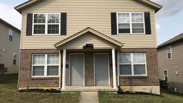A two-story house with a front porch, a brick foundation, and a central door.