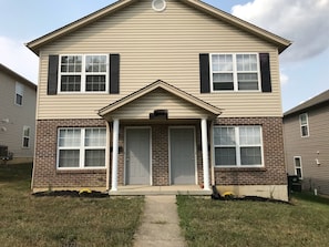 A two-story house with a front porch, a brick foundation, and a central door.