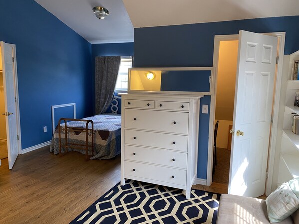 A bedroom with a bed, dresser, and a window with curtains.