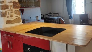 Een keuken met een houten aanrechtblad, rode kastjes en een zwarte oven.