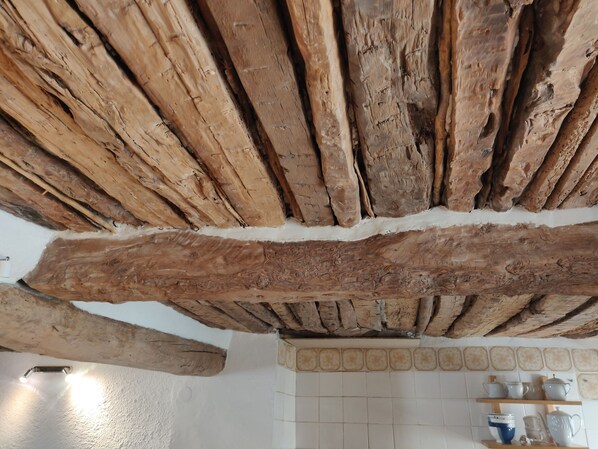 A rustic kitchen with exposed wooden beams and a tiled backsplash.