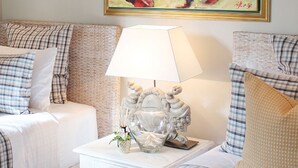 Habitación de hotel con dos camas, ropa de cama a cuadros, una mesita de noche con lámpara y un jarrón decorativo.