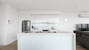 Una cucina moderna con mobili bianchi, un frigorifero in acciaio inossidabile e un'isola integrata con lavello e piano di lavoro.