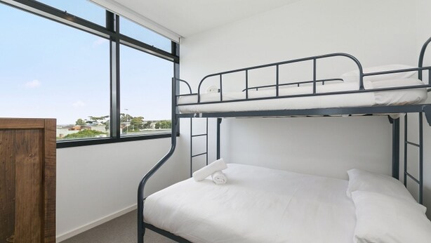 A bunk bed room with a view of the city through a large window. - Whitewater Apartment 201 Ocean Views Walk to Beach (TORQUAY)