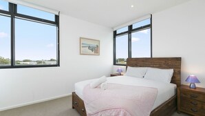 Una camera da letto con un letto grande, due comodini, una testiera in legno e un quadro appeso al muro.