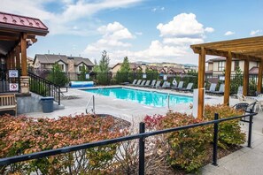 Une piscine avec des chaises longues, un espace de détente couvert et une terrasse clôturée.