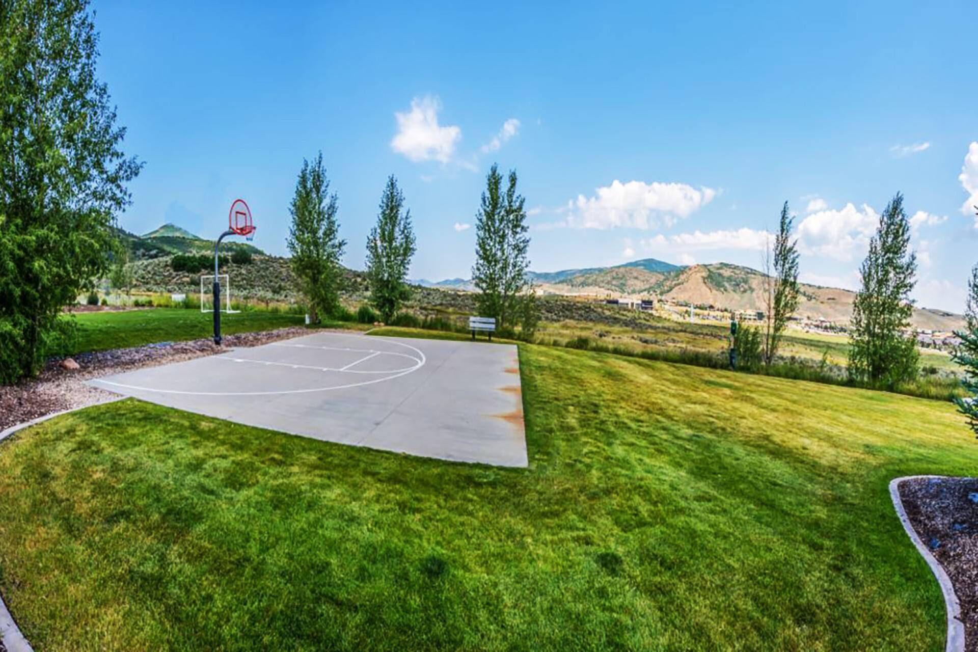 Quadra de basquete com vista desobstruída da paisagem ao redor, incluindo árvores e colinas distantes.