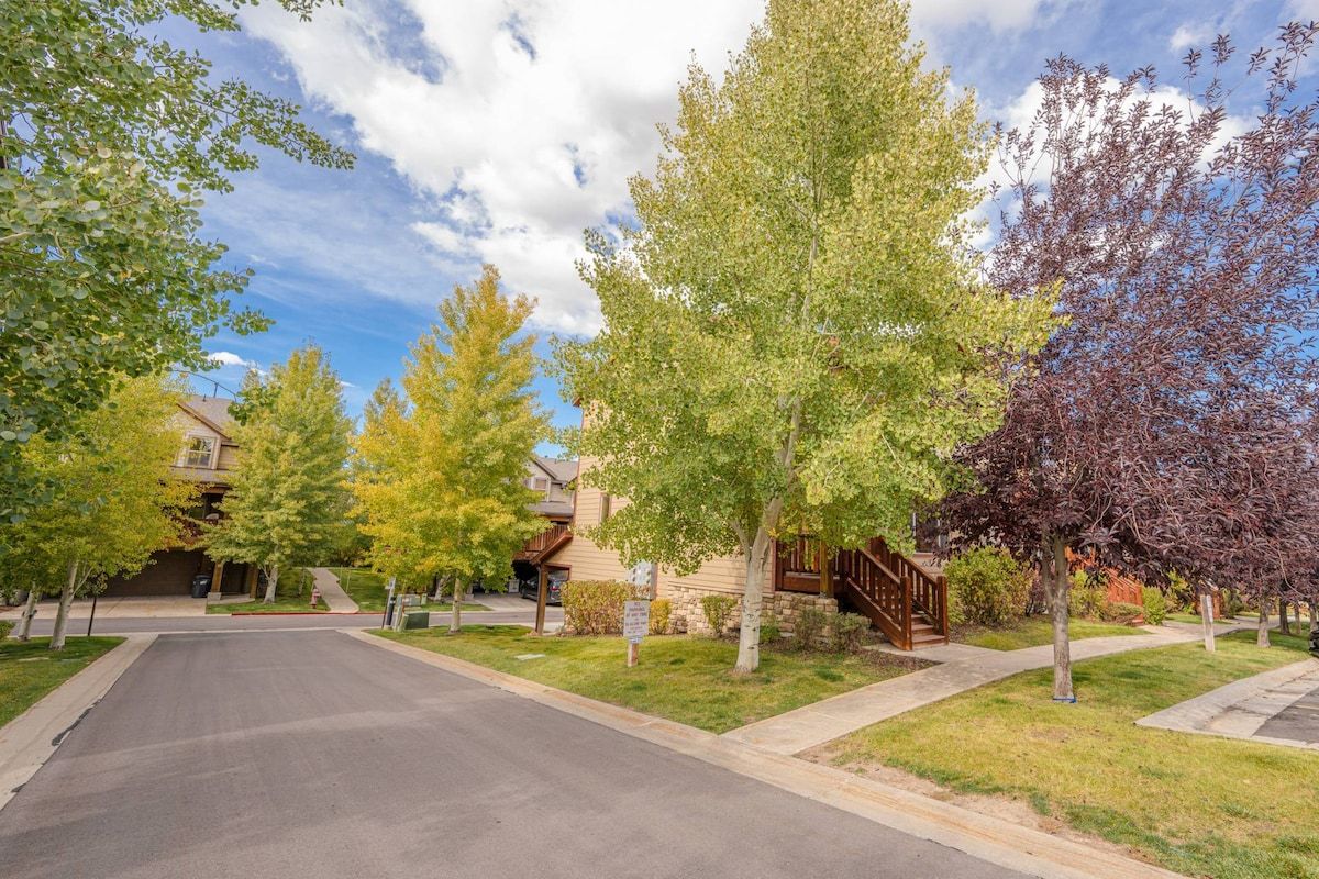 Una strada residenziale con case, cielo sereno e alberi.