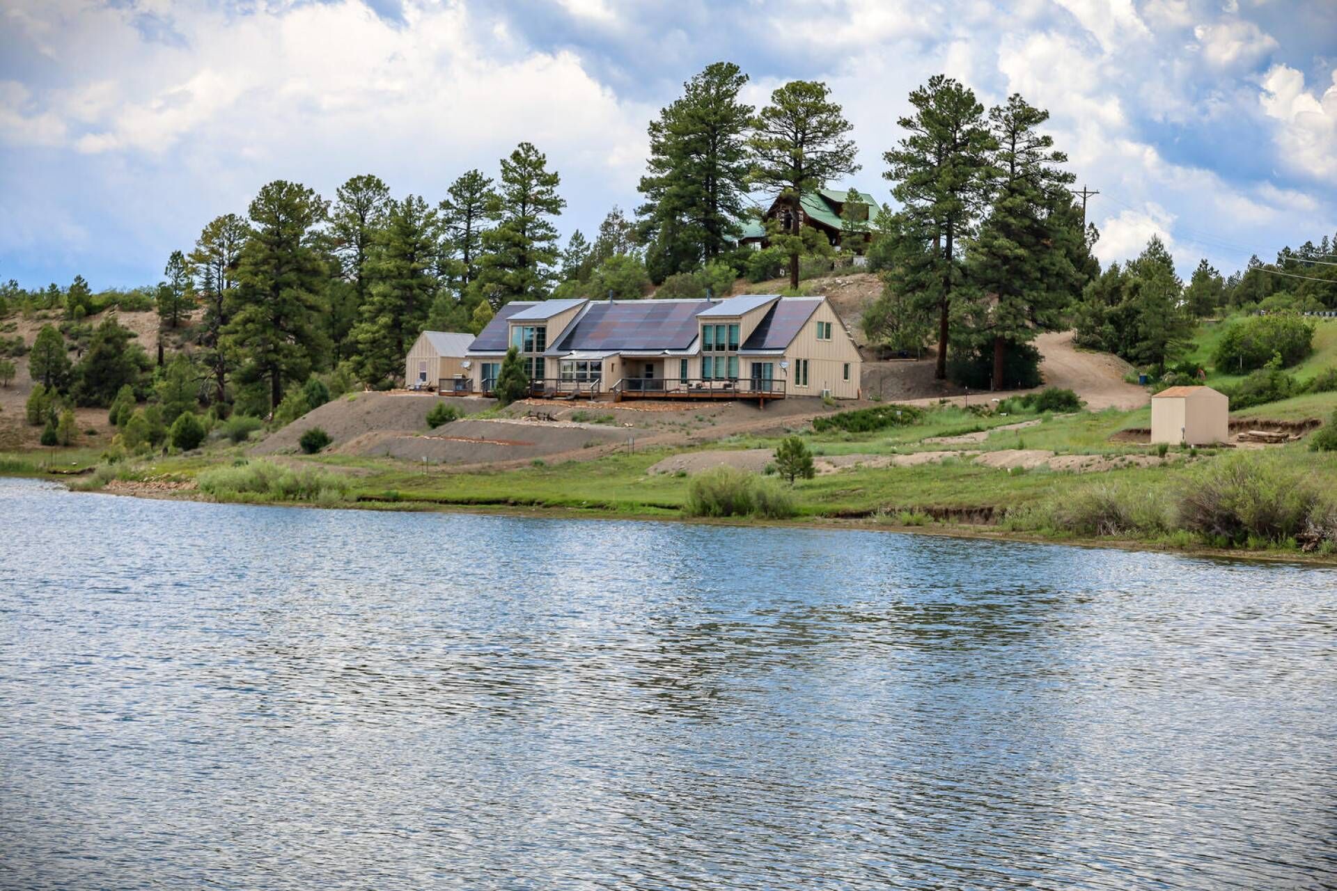Una cabaña junto al lago con una amplia terraza y un espacio exterior cubierto.