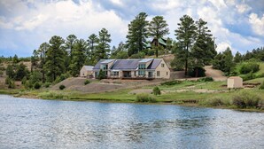 A lakeside cabin with a large deck and a covered outdoor area.