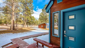 Una cabaña con puerta azul, terraza de madera y mesa de picnic.