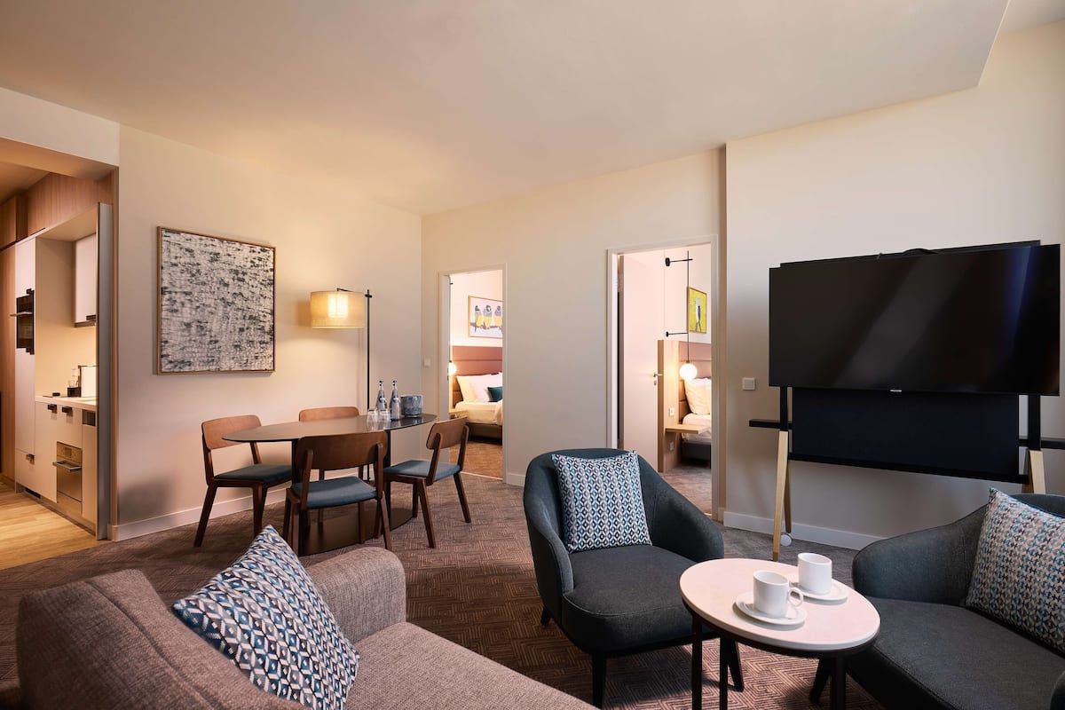 Ein modernes Hotelzimmer mit Wohnbereich, Essbereich und Fernseher.