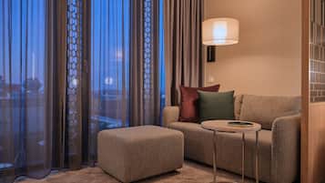 A modern living room with a sofa, ottoman, and a floor lamp.